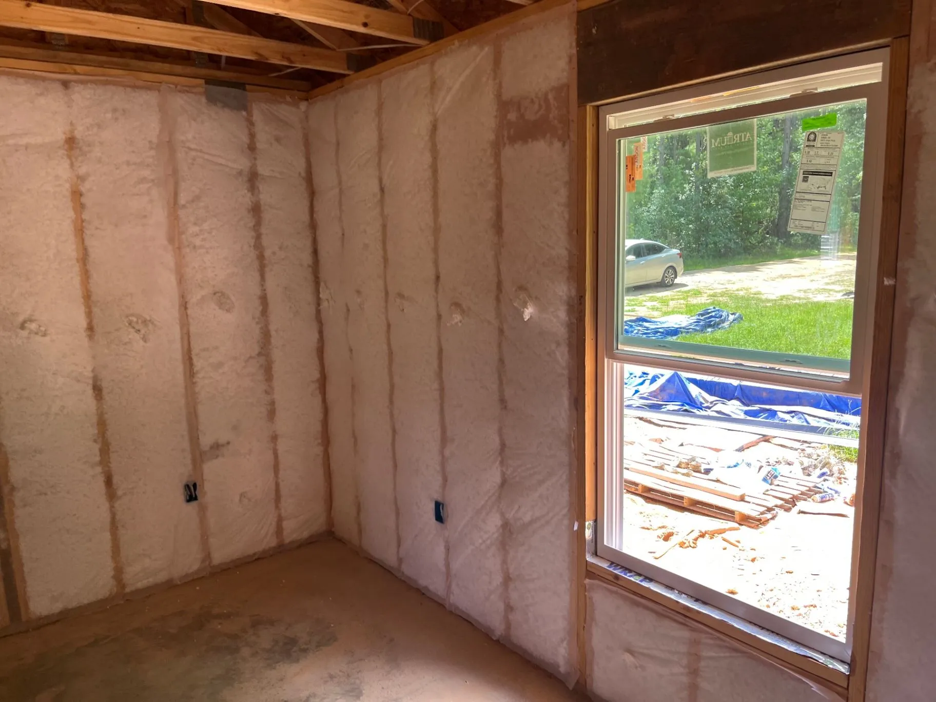 Net-and-blow wall insulation filling open wall cavities around a window