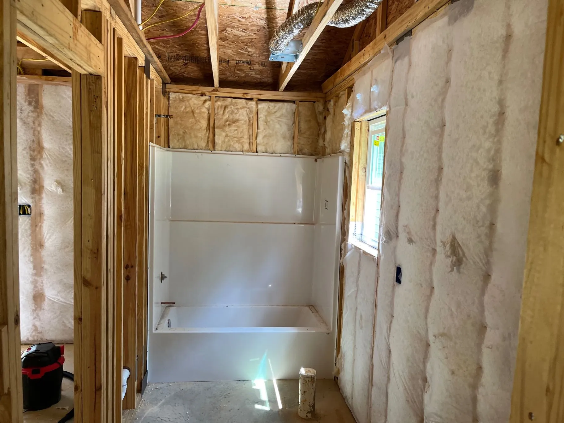 Net-and-blow wall insulation installed in open wall cavities beside an exposed doorway and ductwork